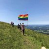 Person trägt beim Wandern eine Regenbogenflagge