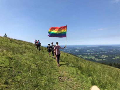 Person trägt beim Wandern eine Regenbogenflagge